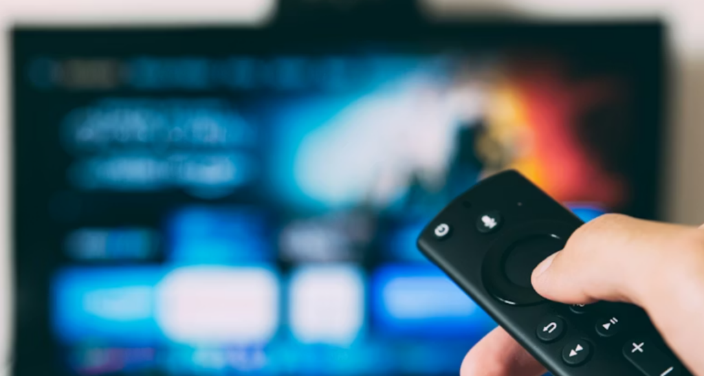 From Streaming to Gaming: How Canadians Spend Digital Leisure Time A hand holding a remote control with a blurred streaming screen in the background